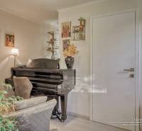 7-izbový rodinný dom s úžasným výhľadom v prestížnej lokalite Devín - Interiér rodinného domu s pianom, kreslom a dekoračnými rastlinami, podlaha s dreveným dekorom.