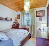 7-izbový rodinný dom s úžasným výhľadom v prestížnej lokalite Devín - Spálňa v rodinnom dome s dreveným stropom, lustrami a dekorovanými stenami.