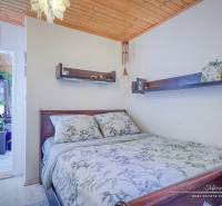 Rekreačná chata s úžasným výhľadom v prestížnej lokalite Devín - Spálňa v Chate s dreveným stropom, kvetinami a poličkami nad posteľou.