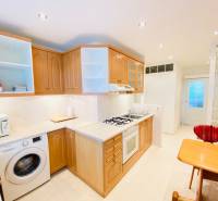 NA PRENÁJOM PRIESTRANNÝ 3-IZBOVÝ BYT V SKVELEJ LOKALITE, UL. SLOBODY - Kuchyňa v 3-izbovom byte s drevenými skrinkami, pultom a sporákom.