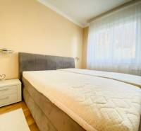 NA PRENÁJOM PRIESTRANNÝ 3-IZBOVÝ BYT V SKVELEJ LOKALITE, UL. SLOBODY - Spálňa s posteľou, nočný stolík, svetlá stena a podlaha s dreveným dekorom.