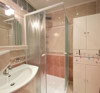 NA PRENÁJOM PRIESTRANNÝ 3-IZBOVÝ BYT V SKVELEJ LOKALITE, UL. SLOBODY - Kúpeľňa v 3-izbovom byte s priehľadným sprchovacím kútom, bielym nábytkom a umývadlom.