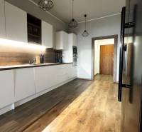 NA PRENÁJOM NADŠTANDARDNÝ 2-IZBOVÝ BYT V CENTRE MESTA - Kuchyňa v 2-izbovom byte s bielymi skrinkami a podlahou s dreveným dekorom.