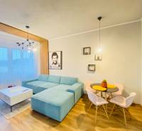 NA PRENÁJOM NADŠTANDARDNÝ 2-IZBOVÝ BYT V CENTRE MESTA - Obývacia izba v 2-izbovom byte s modrým gaučom a podlahou s dreveným dekorom.