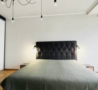 NA PRENÁJOM NADŠTANDARDNÝ 2-IZBOVÝ BYT V CENTRE MESTA - Spálňa v 2-izbovom byte so svetelnými závesmi a posteľou, podlaha s dreveným dekorom.