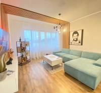 NA PRENÁJOM NADŠTANDARDNÝ 2-IZBOVÝ BYT V CENTRE MESTA - Obývacia izba s tyrkysovou sedačkou, podlahou s dreveným dekorom a moderným osvetlením v 2-izbovom byte.