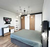 NA PRENÁJOM NADŠTANDARDNÝ 2-IZBOVÝ BYT V CENTRE MESTA - Spálňa v 2-izbovom byte s podlahou s dreveným dekorom, obrazom a minimalistickým lustrom.