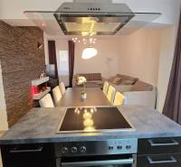 HD REALITY, Vám ponúka na Predaj 3-izbový Apartmán + Garážové státie - Kuchyňa v 3-izbovom byte s jedálenským stolom, tehlovým obkladom a podlahou s dreveným dekorom.