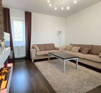 HD REALITY, Vám ponúka na Predaj 3-izbový Apartmán + Garážové státie - Obývačka v 3-izbovom byte s kamennou stenou a podlahou s dreveným dekorom.