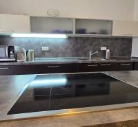 HD REALITY, Vám ponúka na Predaj 3-izbový Apartmán + Garážové státie - Kuchyňa v 3-izbovom byte s varnou doskou, mikrovlnkou a dreveným dekorom pracovnej dosky.