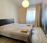 HD REALITY, Vám ponúka na Predaj 3-izbový Apartmán + Garážové státie - Spálňa s veľkou posteľou a stenou s lesnou tapetou, podlaha s dreveným dekorom.