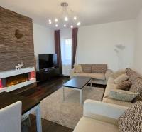 HD REALITY, Vám ponúka na Predaj 3-izbový Apartmán + Garážové státie - Obývačka v 3-izbovom byte s krbom, podlahou s dreveným dekorom a pohodlným sedením.