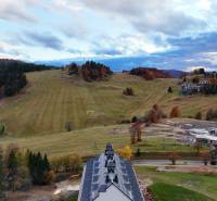 HD REALITY, Vám ponúka na Predaj 3-izbový Apartmán + Garážové státie - Lyžiarske svahy a lesy v Donovaloch s horskými budovami v pozadí.