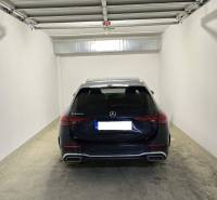 HD REALITY, Vám ponúka na Predaj 3-izbový Apartmán + Garážové státie - Garáž s autom Mercedes-Benz C223d s betónovou podlahou a bielymi stenami.