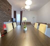 HD REALITY, Vám ponúka na Predaj 3-izbový Apartmán + Garážové státie - Jedálenský stôl v 3-izbovom byte s kamenným obkladom a pohodlnými stoličkami.