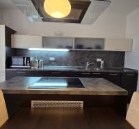 HD REALITY, Vám ponúka na Predaj 3-izbový Apartmán + Garážové státie - Kuchyňa v 3-izbovom byte s varnou doskou, mikrovlnkou a tmavými skrinkami.