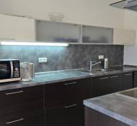 HD REALITY, Vám ponúka na Predaj 3-izbový Apartmán + Garážové státie - Kuchyňa v 3-izbovom byte, s tmavými skrinkami a spotrebičmi na pracovnej doske.