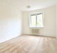 SEČOVSKÁ, 2-i tehlový byt, 56 m2, orientácia V a Z - OBKLOPENÝ ZELEŇOU - Prázdna izba s podlahou s dreveným dekorom, oknom a radiátorom v 2-izbovom byte.