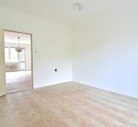 SEČOVSKÁ, 2-i tehlový byt, 56 m2, orientácia V a Z - OBKLOPENÝ ZELEŇOU - Biela miestnosť v 2-izbovom byte s podlahou s dreveným dekorom a výhľadom do obývacej izby.