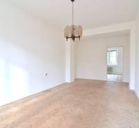 SEČOVSKÁ, 2-i tehlový byt, 56 m2, orientácia V a Z - OBKLOPENÝ ZELEŇOU - Priestranná izba v 2-izbovom byte s podlahou s dreveným dekorom a závesným svietidlom.