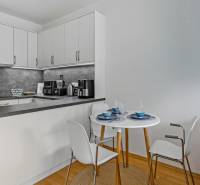 Slnečný 3i byt pod lesom, 74m2, balkón, parking, pivnica, Hainburg - Kuchynský kút s bielymi skrinkami, stolom a podlahou s dreveným dekorom, 3-izbový byt.