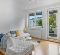 Slnečný 3i byt pod lesom, 74m2, balkón, parking, pivnica, Hainburg - Obývačka v 3-izbovom byte s pohovkou, balkónovými dverami a podlahou s dreveným dekorom.