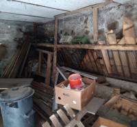 Hospodárska usadlosť  - Skladový priestor s rôznymi predmetmi v rodinnom dome, miestnosť s kameňmi a drevenými prvkami.