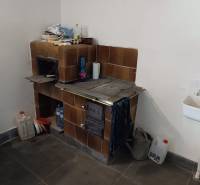 Hospodárska usadlosť  - Kachľová pec vedľa umývadla v interiéri rodinného domu.