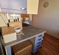 3 izbový byt Zlaté Moravce - Kuchyňa v 3-izbovom byte s modrými skrinkami a podlahou s dreveným dekorom.