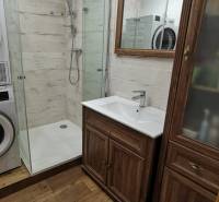 3 izbový byt Zlaté Moravce - Kúpeľňa so sprchovacím kútom, práčkou a podlahou s dreveným dekorom v 3-izbovom byte.