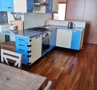 3 izbový byt Zlaté Moravce - Kuchyňa v 3-izbovom byte s farebnými skrinkami a podlahou s dreveným dekorom.