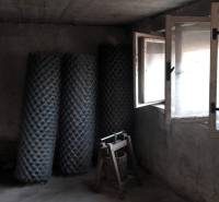 Rodinný dom v obci Dobrá Voda  - Betónová miestnosť v rodinnom dome s rolami pletiva a otvoreným oknom.