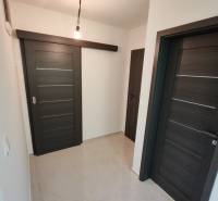 – Podpivničený RD po kompletnej rekonštrukcii - Chodba v 3-izbovom byte s tmavými posuvnými dverami a svetlou podlahou.