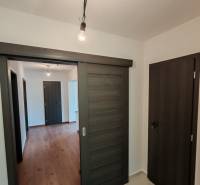 – Podpivničený RD po kompletnej rekonštrukcii - Interiér 3-izbového bytu s podlahou s dreveným dekorom a posuvnými dverami.