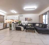 Tri Vody - 4-izbový rodinný dom s bazénom | Most pri Bratislave – Baza - Svetlá obývacia izba v rodinnom dome s kuchyňou a veľkou pohovkou.