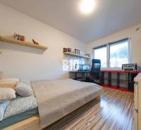 Tri Vody - 4-izbový rodinný dom s bazénom | Most pri Bratislave – Baza - Spálňa v rodinnom dome s pracovným stolom, policami a podlahou s dreveným dekorom.