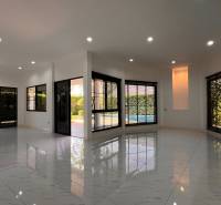 ÚTULNÁ 3 SPÁLŇOVÁ VILA S BAZÉNOM - EAST PATTAYA - Interiér vily s bielymi podlahami a veľkými oknami s výhľadom na záhradu.