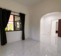 ÚTULNÁ 3 SPÁLŇOVÁ VILA S BAZÉNOM - EAST PATTAYA - Interiér vily s kachľovou podlahou, oblúkovými dverami a závesmi na okne.