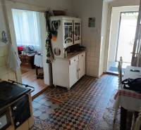 Hospodárska usadlosť s 3,6 hektárovým pozemkom na samote Nová Baňa - Vidíme kuchyňu s kachľovou dlažbou, sporák a starožitnú komodu v rodinnom dome.