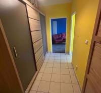 Veľký 2-izb. byt na ul. Vranovská, Petržalka, lodžia, 4.p./7 - Chodba garsónky s dlažbou, skriňami a žltými stenami, vedie do miestnosti s modrými stenami.