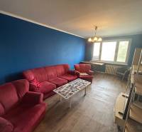 Veľký 2-izb. byt na ul. Vranovská, Petržalka, lodžia, 4.p./7 - Garsónka so sedačkou, modrou stenou a podlahou s dreveným dekorom.