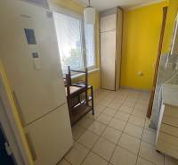 Veľký 2-izb. byt na ul. Vranovská, Petržalka, lodžia, 4.p./7 - Kuchyňa garsónky so žltými stenami, chladničkou a dlažbou na podlahe.