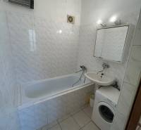 Veľký 2-izb. byt na ul. Vranovská, Petržalka, lodžia, 4.p./7 - Kúpeľňa v garsónke s vaňou, umývadlom, práčkou a dlažbou s bielymi obkladmi.