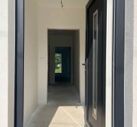 Novostavba- 4-izbový rodinný dom, Super cena - Vstupná chodba v rodinnom dome s betónovou podlahou a čiernymi dverami.