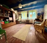 Dom v Budmericiach s možnosťou rekreácie aj trvalého bývania - Obývacia izba v rodinnom dome s podlahou s dreveným dekorom a starožitným nábytkom.