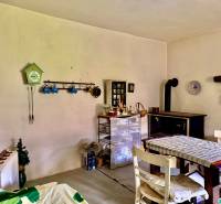 Dom v Budmericiach s možnosťou rekreácie aj trvalého bývania - Jedáleň v rodinnom dome s pecou, stolom a ozdobnými hodinkami na stene.