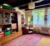 Dom v Budmericiach s možnosťou rekreácie aj trvalého bývania - Izba v rodinnom dome so starým nábytkom a podlahou s dreveným dekorom.