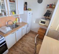 Príjemný 1i byt, zariadený, pivnica, Drobného ul., Dúbravka - Kuchyňa v 1-izbovom byte so sporákom, umývadlom a podlahou s dreveným dekorom.