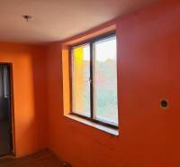 RD TVRDOMESTICE, pozemkom s prístupom z oboch strán - Miestnosť s oranžovými stenami a veľkým oknom, podlaha s dreveným dekorom.