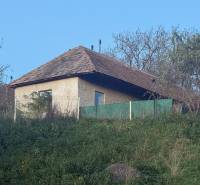 RD TVRDOMESTICE, pozemkom s prístupom z oboch strán - Súčasťou Tvrdomestíc je rodinný dom s drevenou strechou, obklopený zeleňou a plotom.